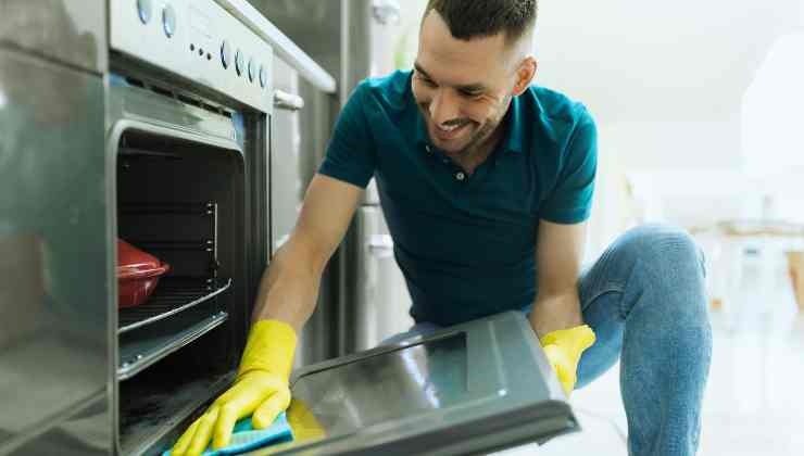 uomo che pulisce forno