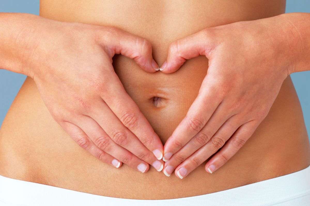 Donna con cuore sulla pancia fatto con le mani